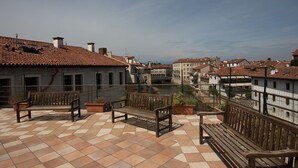 Une terrasse avec un sol carrelé, des bancs en bois et des plantes en pot.