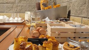Une table de buffet proposant divers desserts, notamment des brownies et des gâteaux, ainsi qu’un coin café avec des tasses et des ustensiles.