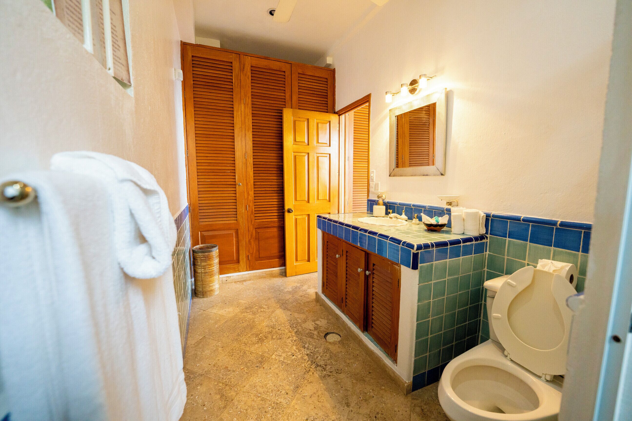 Kylpyhuone, jossa on wc, pesuallas ja puiset kaapit.