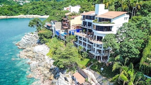 Une propriété située sur la côte, comprenant plusieurs bâtiments, un littoral rocheux et une végétation luxuriante.