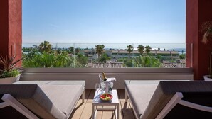 A balcony with two chairs, a table with a bottle and glasses, and a view of the sea and buildings. - Oassium Hotel at Estival Park (Vila-Seca)