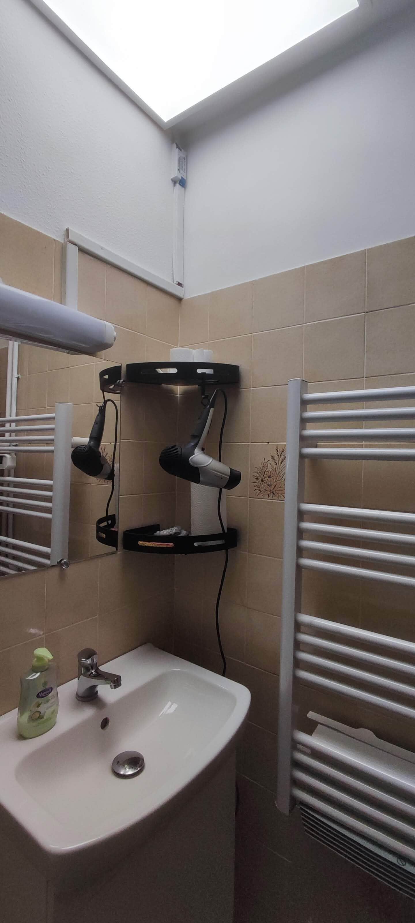 A bathroom with a sink, mirror, towel rack, and a shower area.