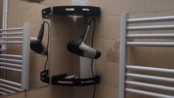 A bathroom with a sink, mirror, towel rack, and a shower area.