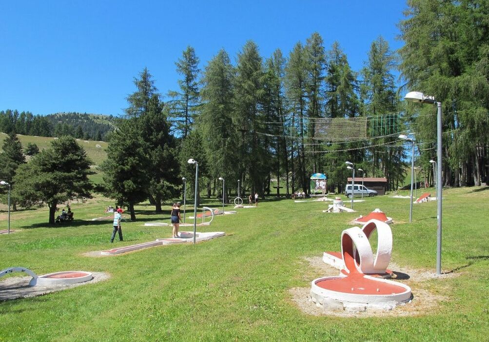 A park with a playground, trees, and a small building.