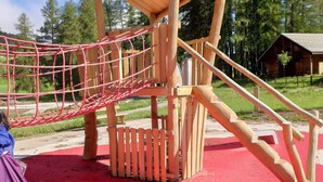 A wooden play structure with a red ground surface and a small shelter. - Superdevoluy545S (Le Dévoluy)