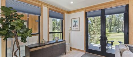 Relax in a serene space with a sofa facing a sliding glass door to a balcony overlooking a well-maintained lawn and trees.