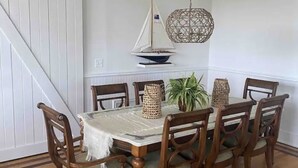 Una sala da pranzo con un tavolo e sedie in legno, un modellino di barca a vela e un lampadario.