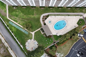 An aerial view of a residential complex with a swimming pool, tennis courts, and a circular garden area. - Emerald Oasis w/ Gulf Views, Pools, Hot Tubs (Destin)