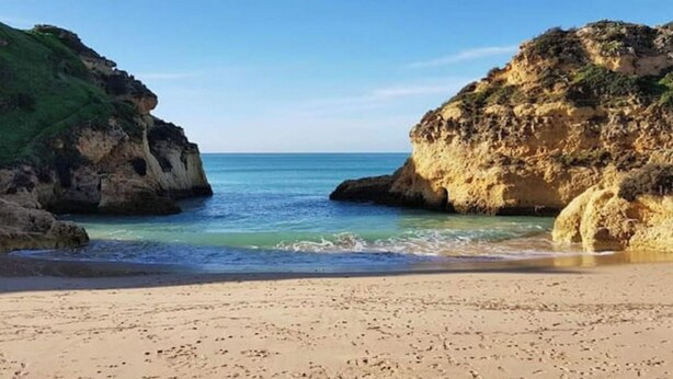 A beach with a sandy shore, rocky cliffs, and calm sea. - Charming, comfortable apartment in a good location (Portimão)