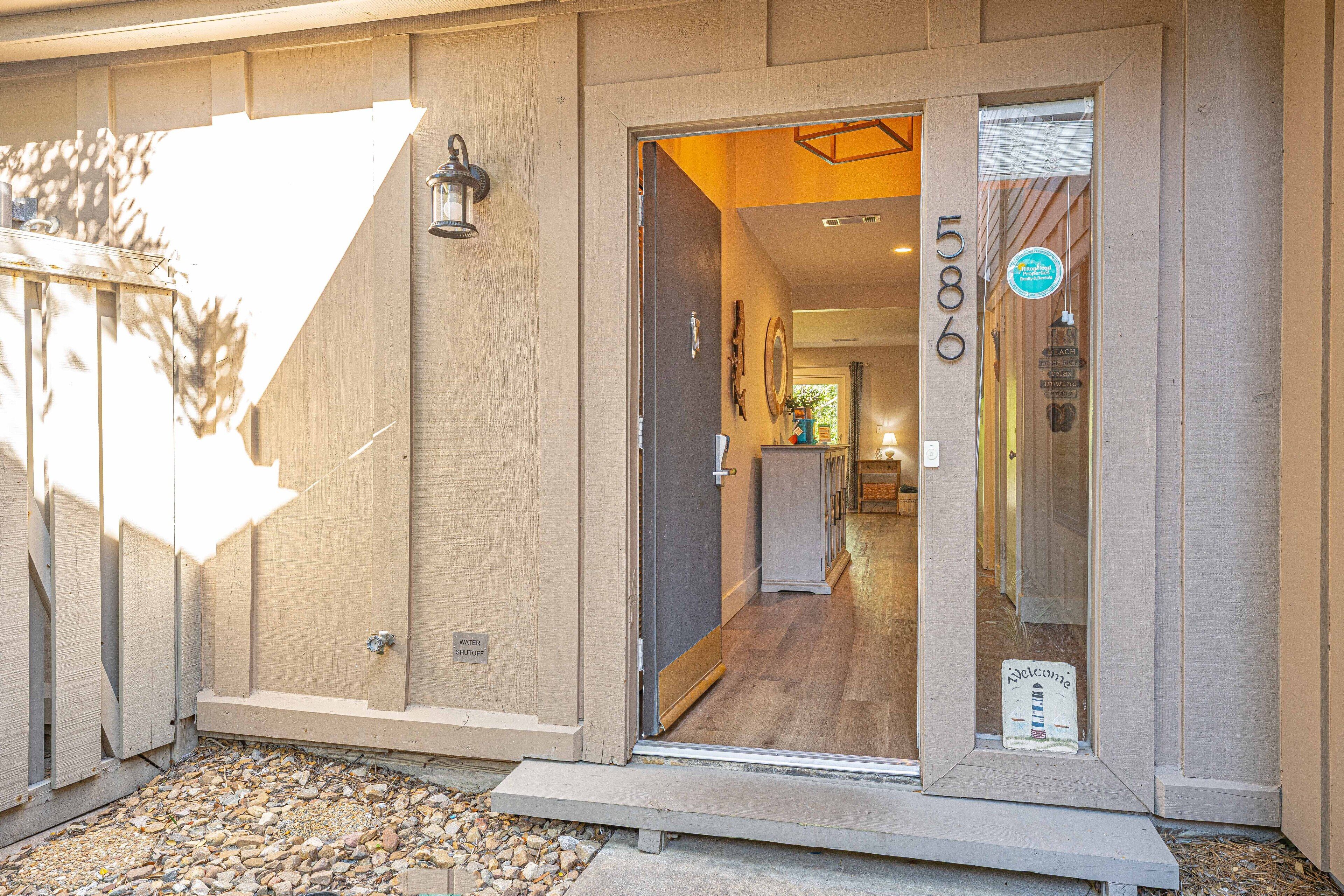 A hotel entrance with a welcoming sign, a water shutoff label, and a view into the interior.