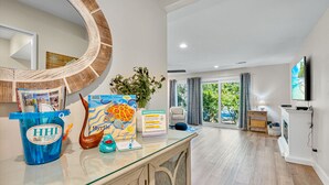 Une chambre d’hôtel avec une table basse en verre, une plante en pot, une carte encadrée et une vue sur l’extérieur grâce à de grandes fenêtres.