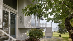 A house with a front porch, a small tree, and a view of the water.