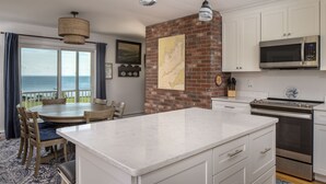 A kitchen with white cabinets, a large island, and a view of the ocean.
