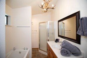 A bathroom with a bathtub, a shower, a sink, and a mirror. - The Duke Cabin - A FOREST LAKES Cabin in the Woods! HOT TUB (Coconino County)