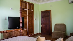 A room with a bed, a television, a wooden wardrobe, and a door. - Old Cam Lodge (Runaway Bay)