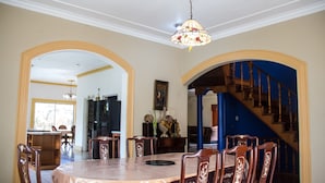 A dining area with a round table, chairs, and a chandelier. There are two archways leading to other rooms. - Old Cam Lodge (Runaway Bay)