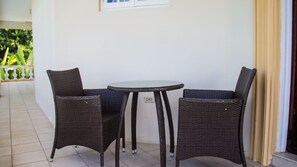 A small, round table with two wicker chairs. The room has a tiled floor and a white wall.