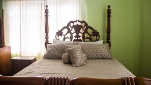 A bed with a wooden headboard, multiple pillows, and a bedside table.
