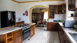 A kitchen with a gas stove, oven, wooden cabinets, and a microwave. - Old Cam Lodge (Runaway Bay)