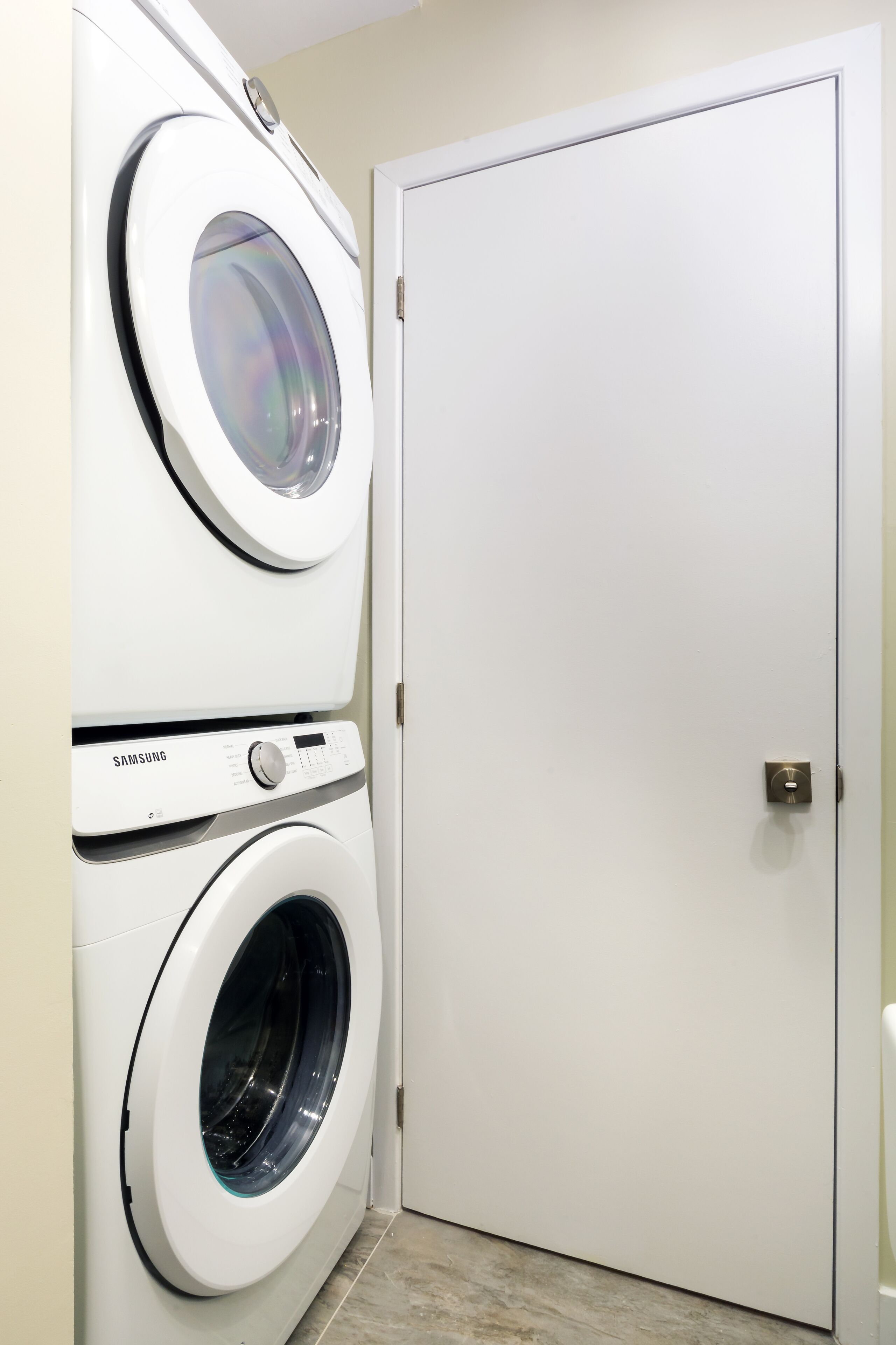 Une buanderie équipée de deux lave-linge Samsung à chargement frontal, de couleur blanche, et dotée d’une porte fermée.