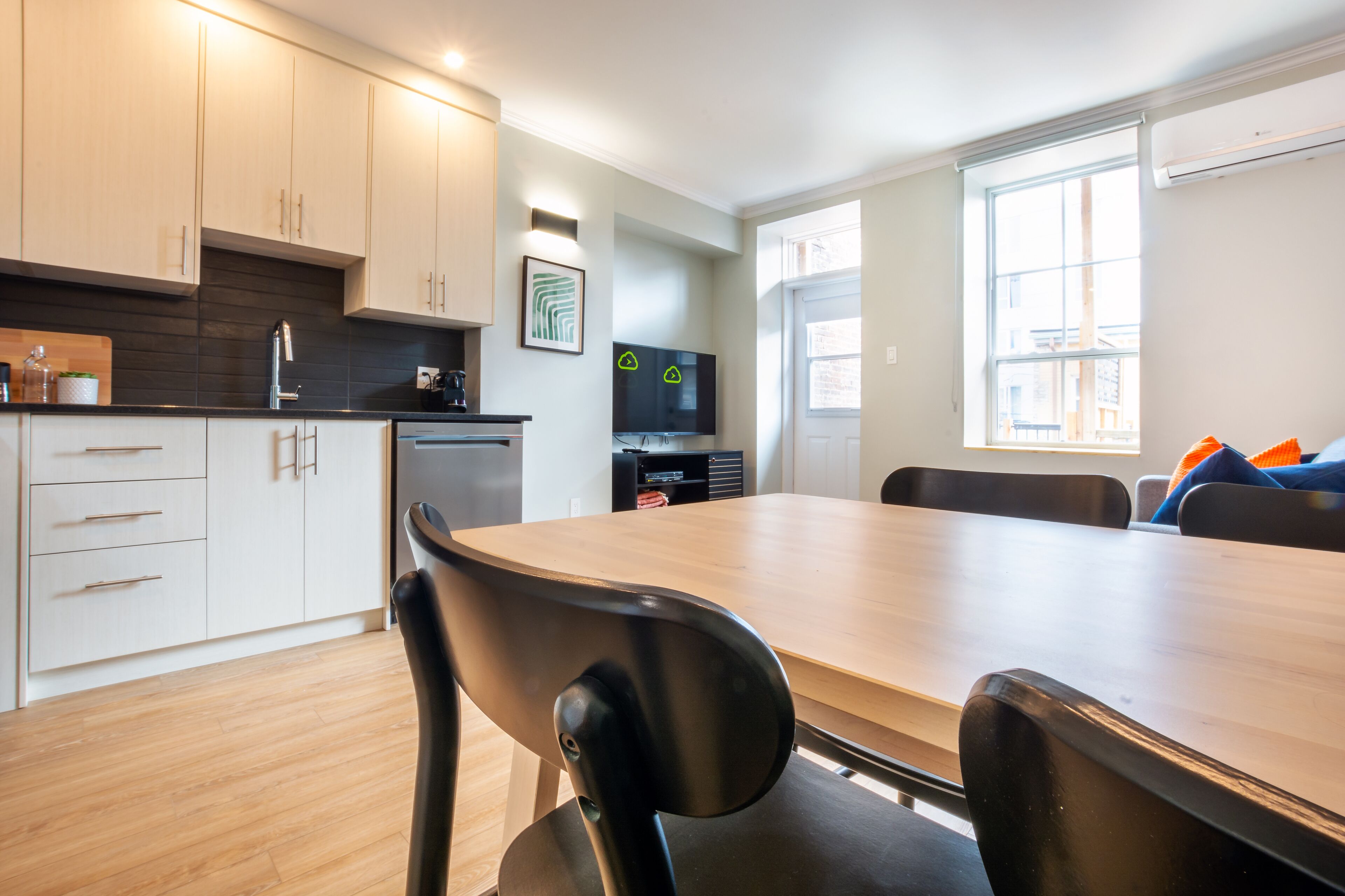 A modern kitchen with white cabinets, a wooden countertop, and a dining area with a large table and chairs.