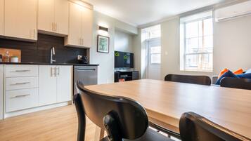 A modern kitchen with white cabinets, a wooden countertop, and a dining area with a large table and chairs.