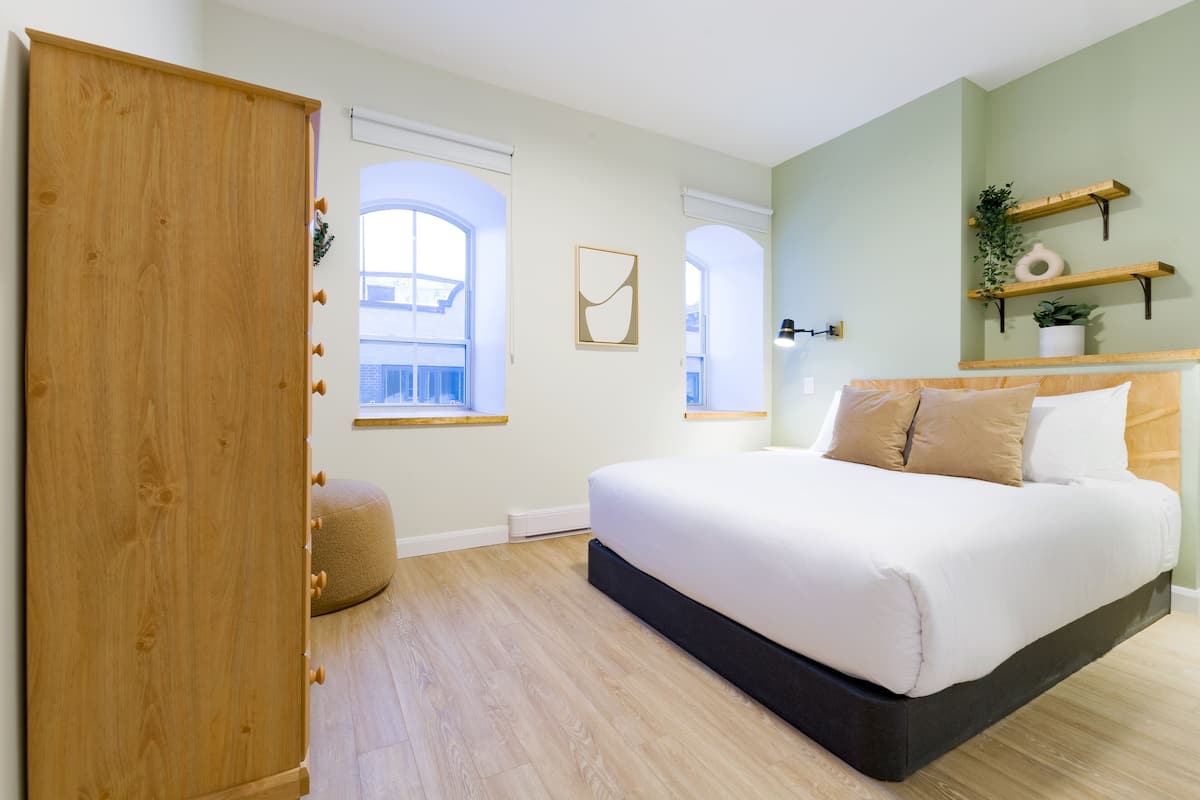 Une chambre à coucher avec un lit, une armoire en bois et une fenêtre donnant sur un beau paysage.