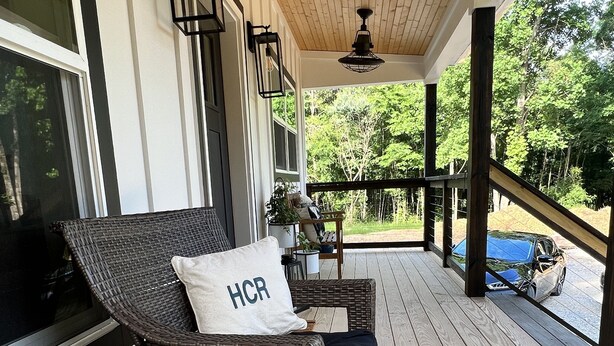 A covered porch with wicker furniture, a wooden barrel, and a view of the outdoors.