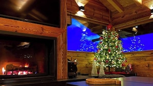 Um quarto aconchegante com lareira, teto de madeira e árvore de Natal.