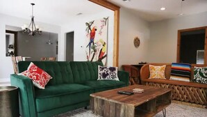 A living room with a green sofa, a wooden coffee table, and a colorful bench. - Dos Pinos Riverside Cottage near DT Kerrville (Kerrville)