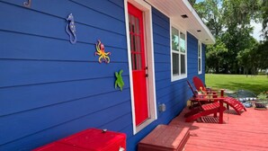 Una casa azul con puerta y buzón rojos, y un banco rojo en el porche.