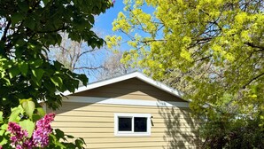 A small, single-story house with a window and a patio area with outdoor furniture.