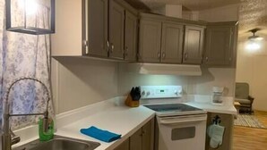 Una cocina con un lavamanos de acero inoxidable, una estufa y alacenas.