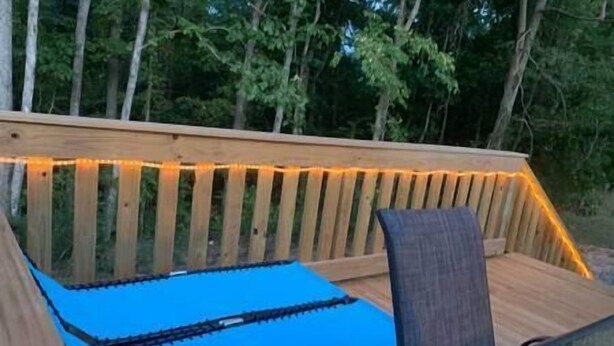 Terraza con un tapete azul, baranda de madera y luces cálidas.