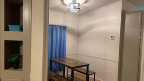 Una habitación pequeña y estrecha con un banco de madera, una cortina azul y una lámpara en el techo.