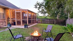 A backyard with a fire pit, two chairs, and a covered patio area. - Cozy and relaxing beach house, Our Little Pearl in Foley. (Foley)