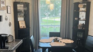 A dining area with a table set for four, surrounded by chairs, with a black cabinet to the left and a black shelving unit to the right. - Cozy and relaxing beach house, Our Little Pearl in Foley. (Foley)