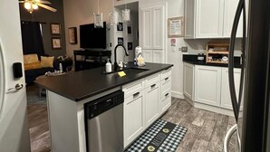 A modern kitchen with a central island, white cabinetry, and a built-in dishwasher. - Cozy and relaxing beach house, Our Little Pearl in Foley. (Foley)