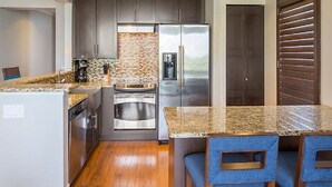 Una cocina moderna con encimeras de granito, electrodomésticos de acero inoxidable y un salpicadero de ladrillo.
