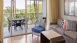 Una sala de estar moderna con sofá, una mesita de centro y un balcón con mobiliario exterior.