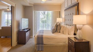 Una habitación de hotel con cama, lámparas de noche, televisor, cómoda y ventilador de techo.