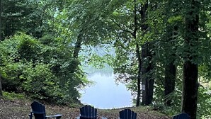 Quatre fauteuils Adirondack sont placés face à un lac, entouré d’une végétation luxuriante.