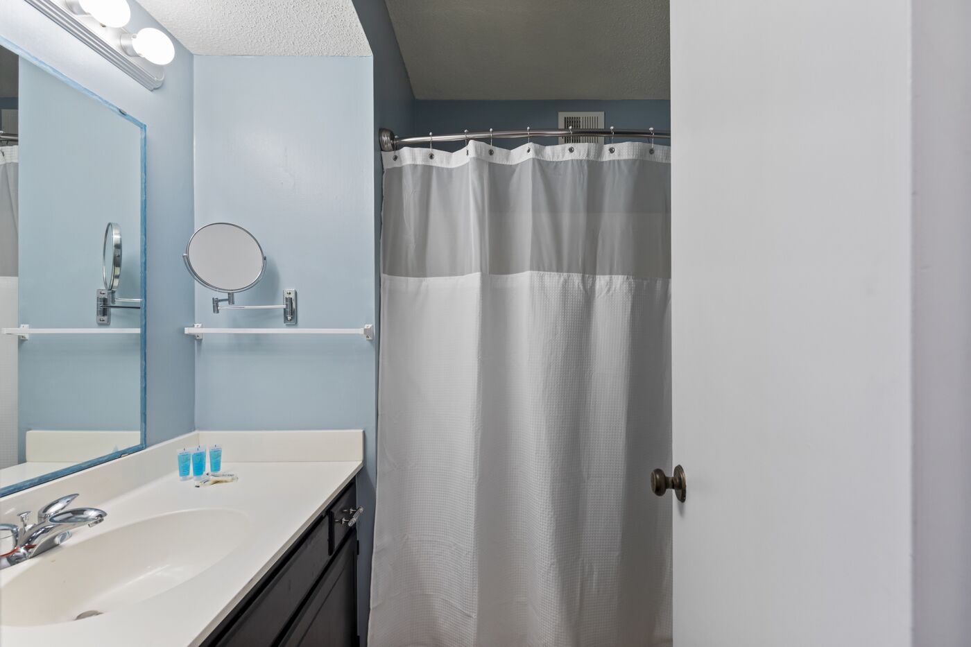 A bathroom with a white sink, mirror, and shower curtain.