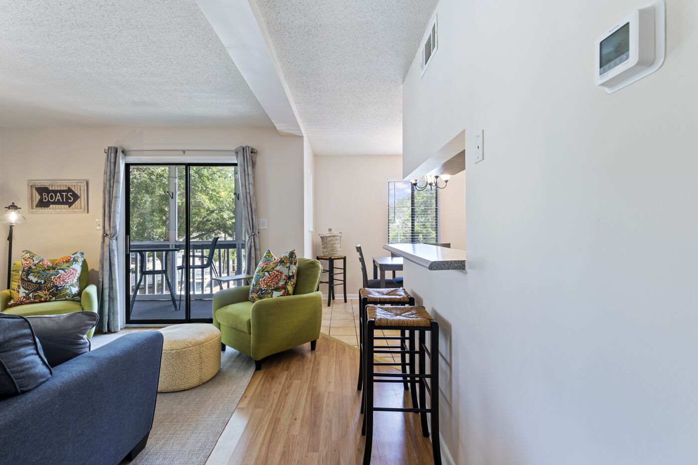 Una sala de estar moderna con un sofá, un sillón verde y un comedor con sillas y una pequeña mesa.