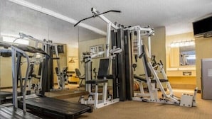 Ein Fitnessstudio mit Cardiogeräten, Krafttrainingsmaschinen und einer Spiegelwand.