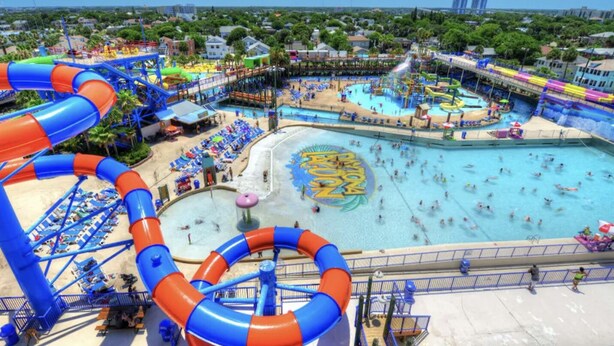 Un parc aquatique doté de plusieurs piscines, de toboggans et d’une grande structure circulaire avec des jeux d’eau.