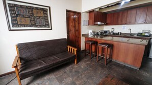 A compact living space with a sofa, a small kitchen area, and a dining table. - VPX HOTEL & Bungalows (Cieneguilla)