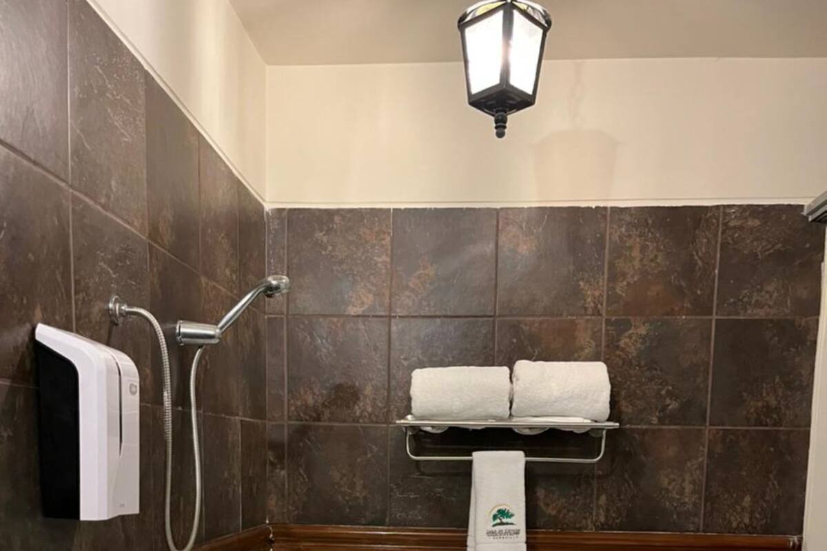 Un baño moderno con una bañera independiente, un cabezal de ducha manual y un perchero con dos toallas.