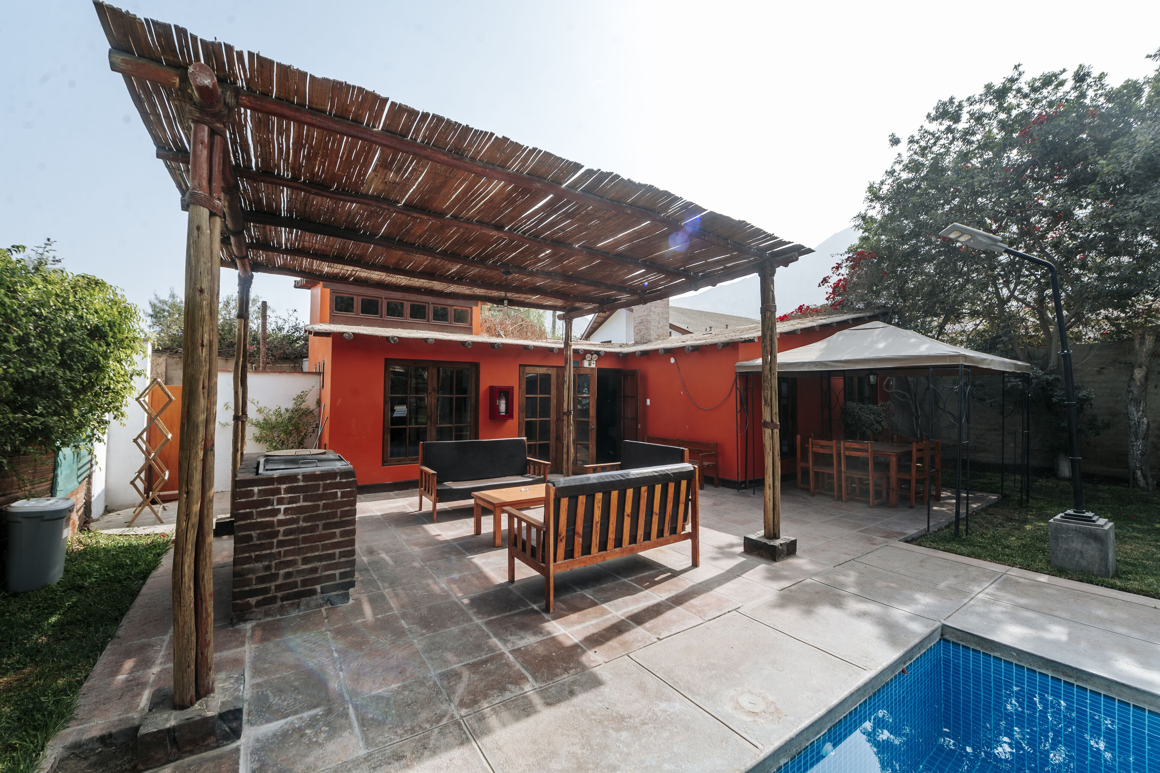 Un patio cubierto con mobiliario exterior, una parrilla de ladrillo y una piscina.