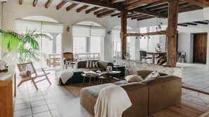 A spacious living area with a large sofa, a wooden chair, and a dining table. - West House (Biaudos)